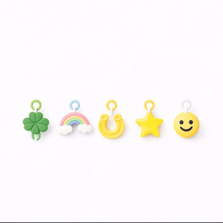 Set of colorful earrings including rainbow, clover, star, and smiley face designs on a white background.