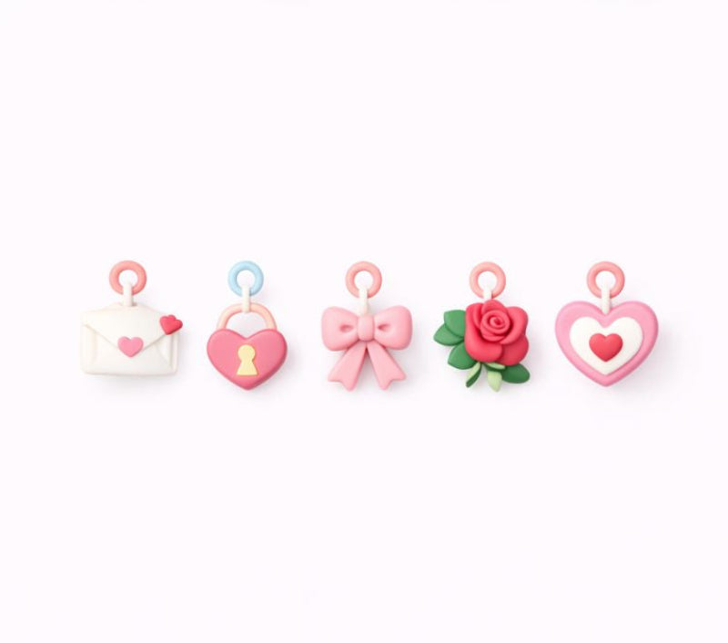Set of decorative charms shaped like an envelope, heart, key, bow, and rose on a white background.