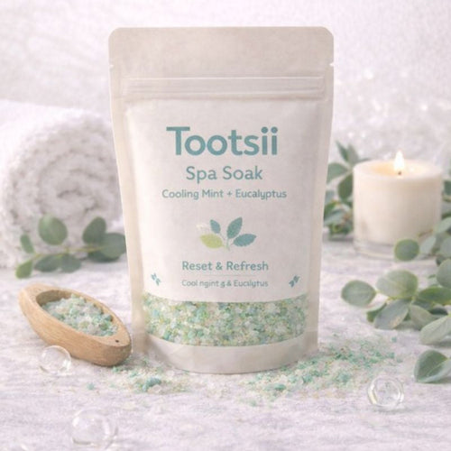 Tootsii Spa Soak packaging with eucalyptus leaves and a candle on a textured surface
